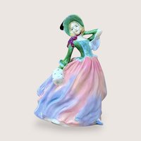 A vertical porcelain figurine of a woman in a wind-swept gown. She wears a vibrant green bodice, a wide-brimmed hat, and a voluminous skirt in blended shades of pink, peach, and lavender. Glossy, fine-bone china texture.