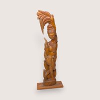 Carved wooden statue of a woman carrying a woven basket on her head, isolated on a light neutral background.