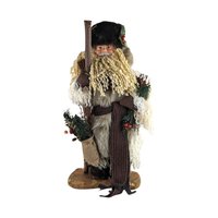 A tall, standing Father Christmas figure in a tan coat and brown fur hat. He has a long curly beard, holds a wooden staff, and carries a burlap sack with pine needles.