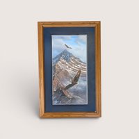 Framed wildlife print showing two bald eagles soaring over a snow covered mountain peak with a dark blue mat.
