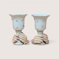 Pair of white porcelain hand vases with pink floral details and gold trim, centered on a plain linen background.