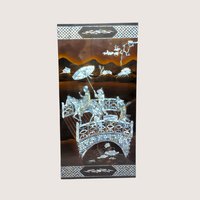 A large rectangular black lacquer wall panel featuring a detailed mother of pearl inlay scene with figures on a bridge.