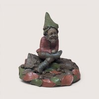 1995 Tom Clark signed Padre gnome figurine sitting on a log base surrounded by autumn leaves on a linen background