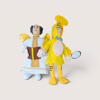 2001 The Three Stooges plush dolls featuring one dressed as an angel holding a book and one dressed as a yellow chicken.