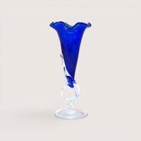 A vintage hand blown studio art glass trumpet vase by Dan Dechard on a soft pink background. Made in 1989, the vase features a rich translucent cobalt blue horn set into a clear sculptural stem and circular clear glass base.
