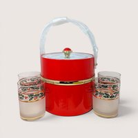 A vintage red ice bucket surrounded by four matching frosted holly glasses on a plain background