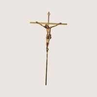 A slim vintage brass colored crucifix wall hanging featuring a detailed bronze tone corpus on a light cream background