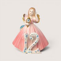 Vintage Josef Originals age 12 birthday girl porcelain figurine holding a gold hand mirror on a linen background.