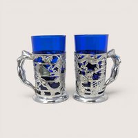 Pair of vintage Japanese silver-plated tankards with cobalt blue glass liners and detailed figural handles.