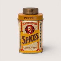A small yellow vintage spice tin featuring a man portrait and a gold shaker cap on a plain white background