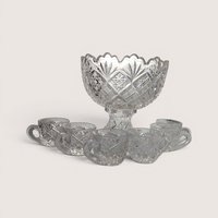 Vintage miniature cut glass punch bowl on a pedestal stand surrounded by six small glass cups.