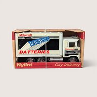 Vintage 1980s white Nylint Ford pressed steel City Delivery box truck featuring Motorcraft Batteries advertising in original box.