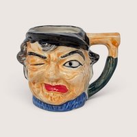 Vintage ceramic character mug shaped like a winking fisherman wearing a black cap and blue sweater.