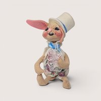 1993 Annalee felt Easter bunny doll wearing a white top hat and floral lace vest against a neutral backdrop.