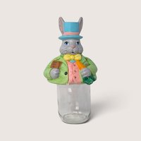 Vintage ceramic Easter bunny mason jar topper wearing a blue top hat sitting on a clear glass jar.