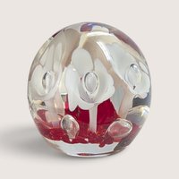 Vintage art glass paperweight featuring white flower motifs suspended over a vibrant red glass base.