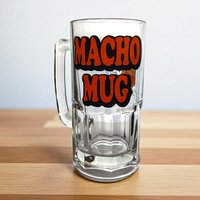 A large, heavy clear glass beer mug featuring a colorful 1979 illustration of the cartoon character Ziggy holding a foaming mug of beer with the word Macho printed above him.