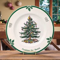 A large round porcelain plate featuring the iconic Spode Christmas tree at the center, decorated with colorful ornaments and topped with a tiny Santa. Bold, festive lettering reads 'Cookies for Santa' around the rim, accented with holly sprigs and a crisp green border.