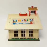 A cream-roofed toy schoolhouse with a red base and carry handle. The texture is a mix of sturdy molded plastic and lithographed paper siding in a rectangular, boxy silhouette.