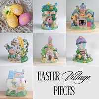 A collage of various colorful Easter-themed miniature buildings and figurines made of ceramic or resin. The collection includes an egg-shaped grocery store, a teapot flower shop, a pastel church, a schoolhouse with a clocktower, a treehouse cottage, and a bunny-filled hot air balloon, all featuring small bunny characters and spring floral accents.