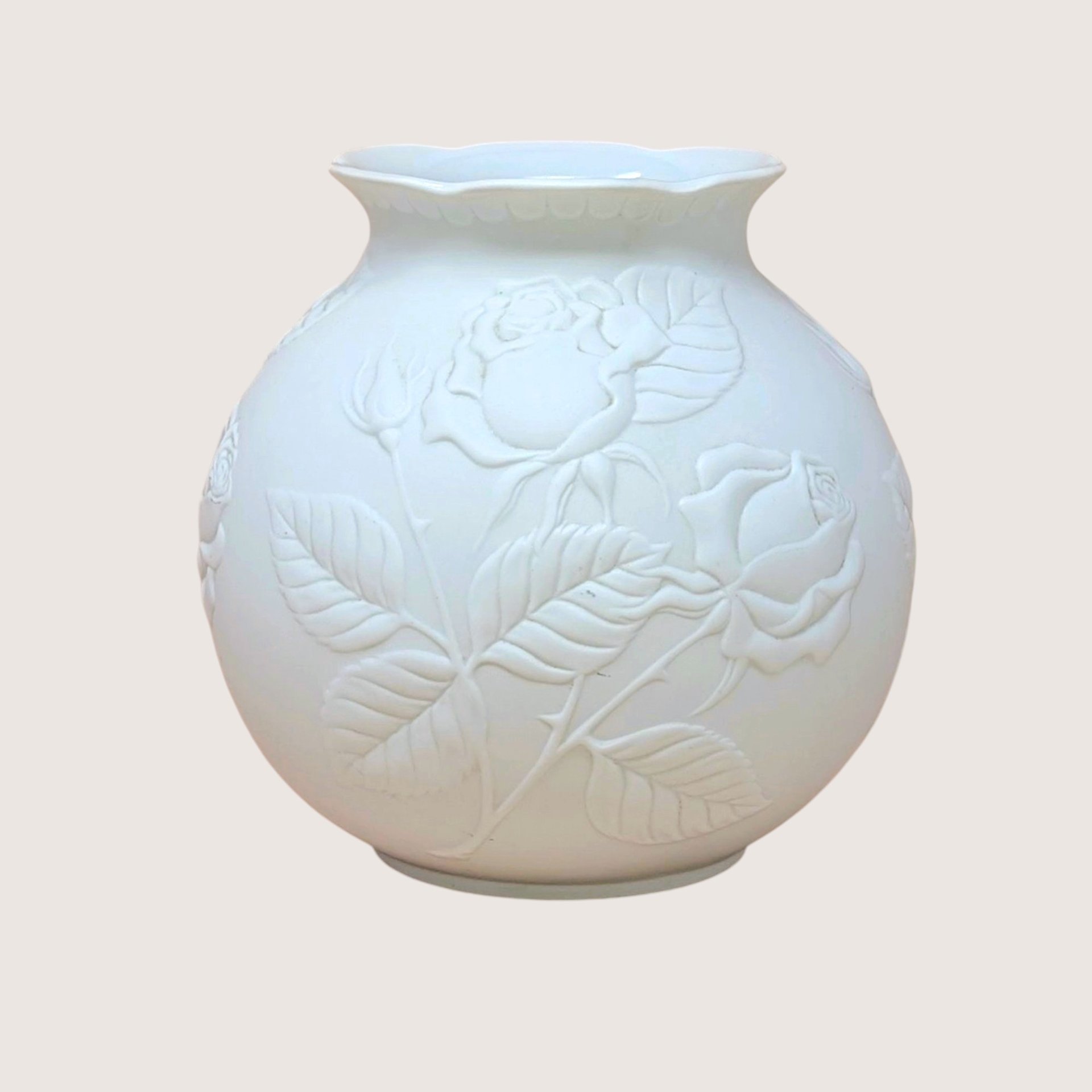 Kaiser West Germany white bisque porcelain vase with a globular body and flared rim. Features a high-relief embossed rose and leaf design with a soft matte finish. 5.5 inches tall.