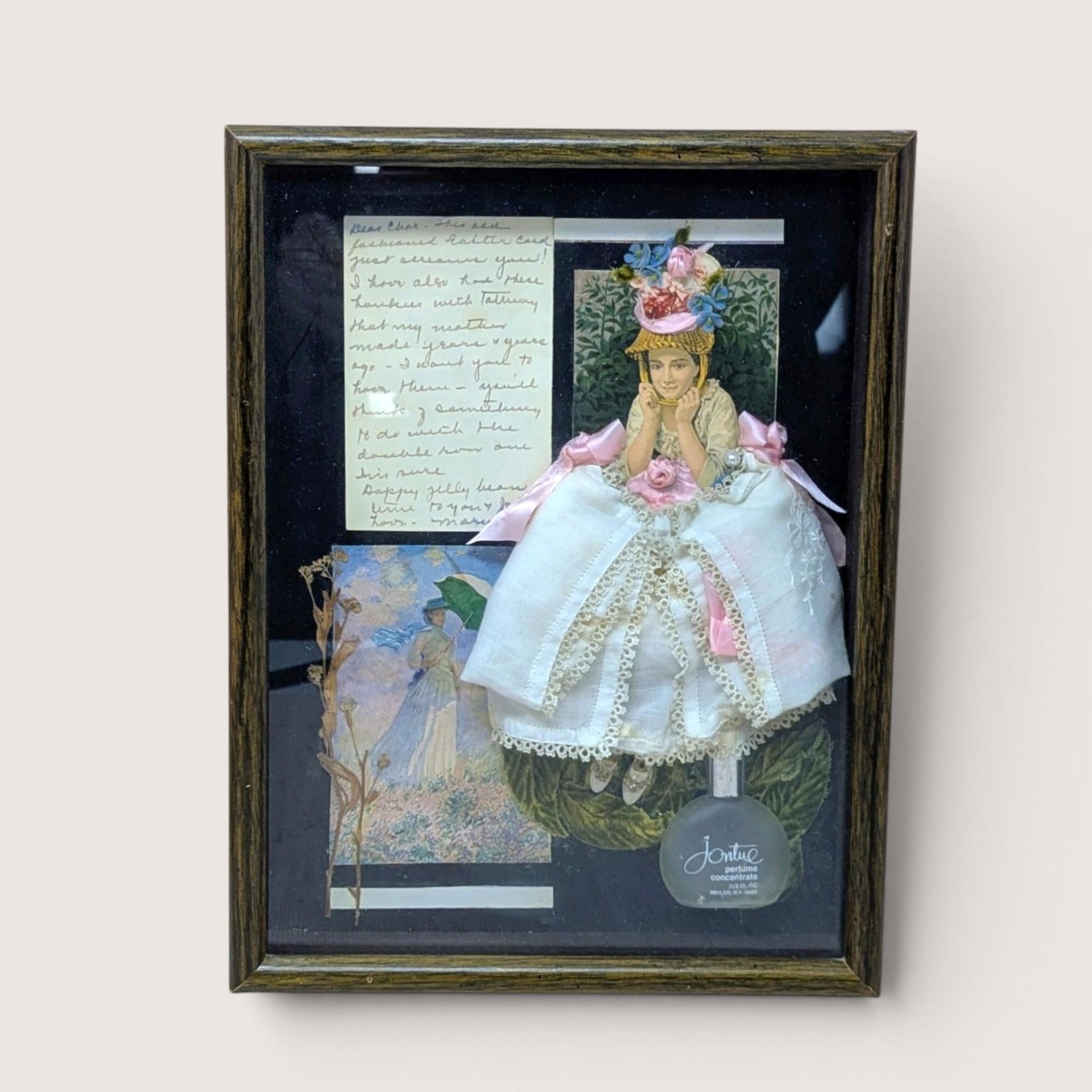 Dark wood shadow box featuring a 3D collage of a Victorian woman in a white lace dress. Black background with a frosted perfume bottle, dried botanicals, and handwritten yellowed paper. Rich, layered multimedia textures.