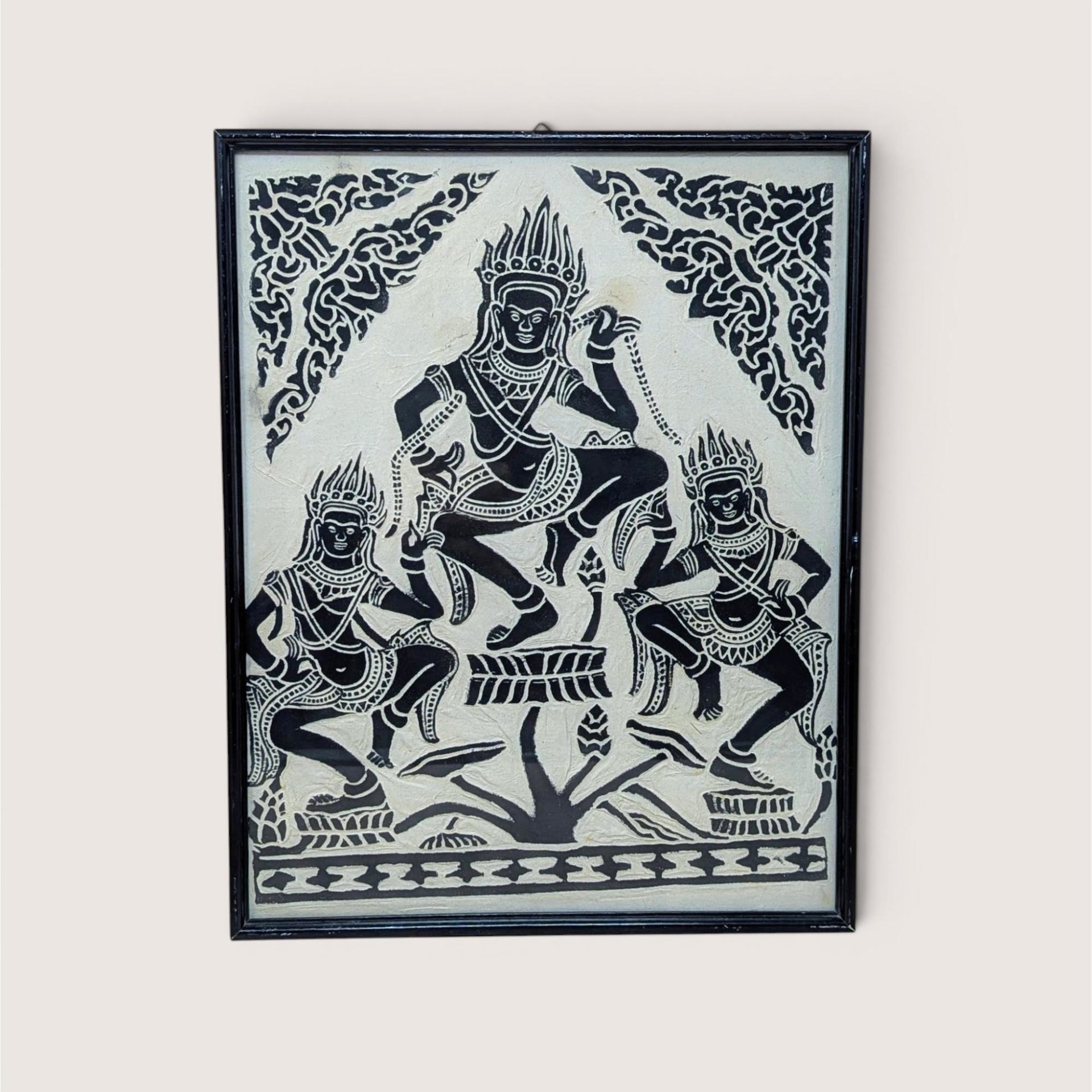 A vertical framed art piece on textured rice paper featuring three Apsara dancers in traditional Cambodian headdresses and poses. Bold black ink on a cream-white background. Framed in a minimalist black wood frame.