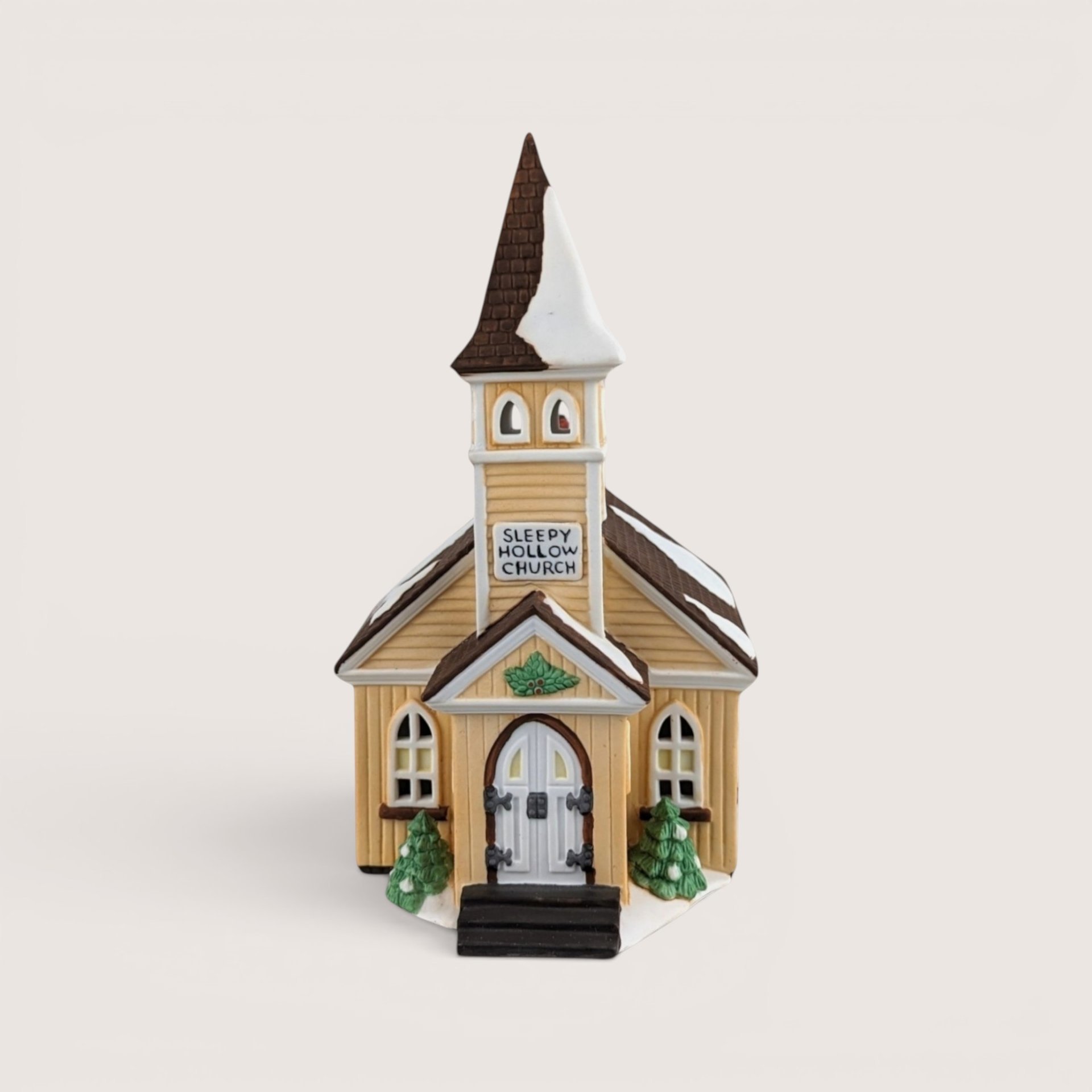 Hand-painted porcelain miniature Sleepy Hollow Church with a yellow facade, snow-dusted brown roof, and a tall steeple.