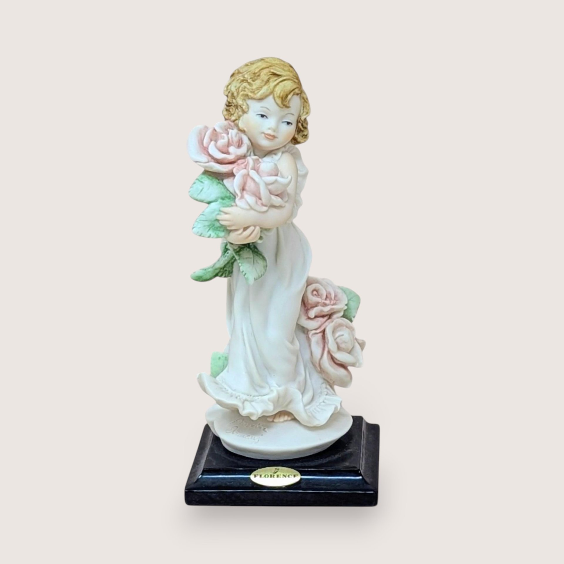 Giuseppe Armani Florence figurine of a young girl holding large pink roses, mounted on a black base.