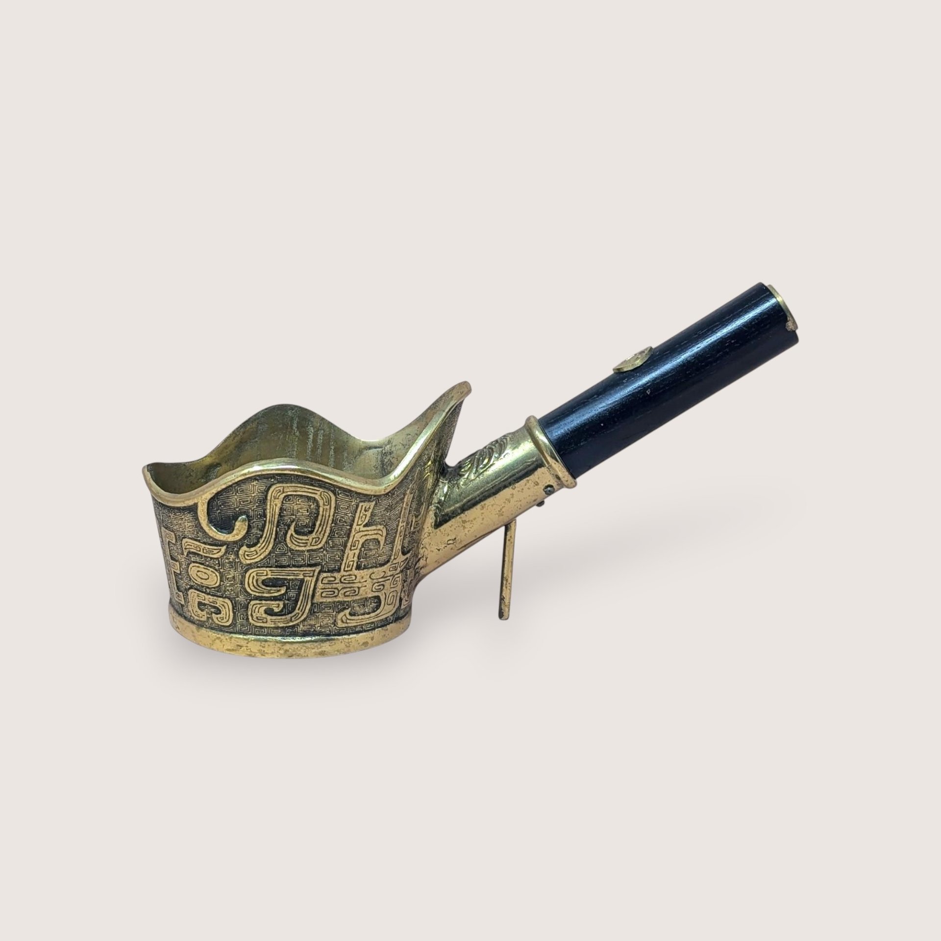 Vintage brass Chinese silk iron with an intricate textured pattern and a dark wooden handle, isolated on a light background.