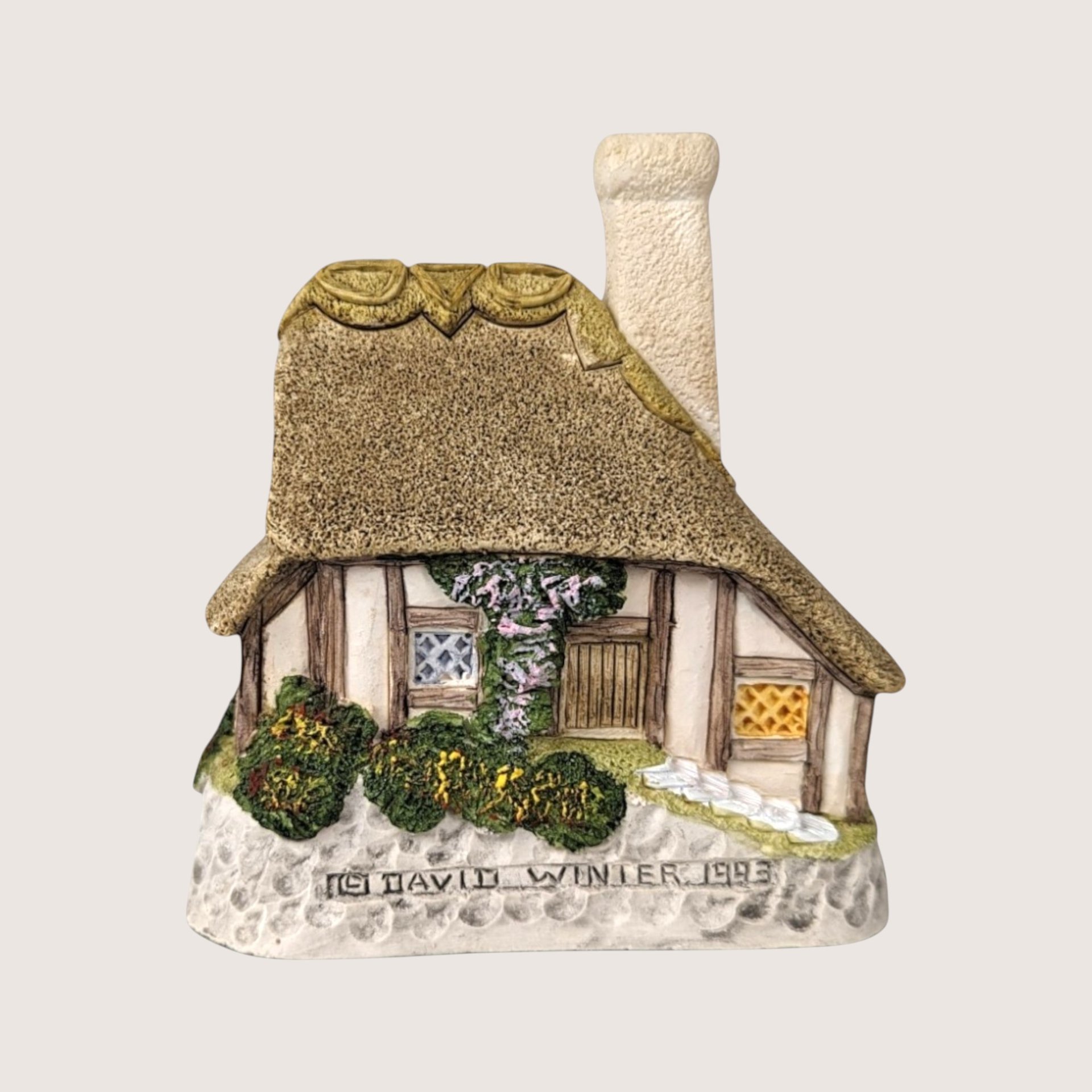 A 1993 David Winter "Crystal Cottage" miniature figurine featuring a detailed thatched roof, half-timbered walls, and a small stone bridge.