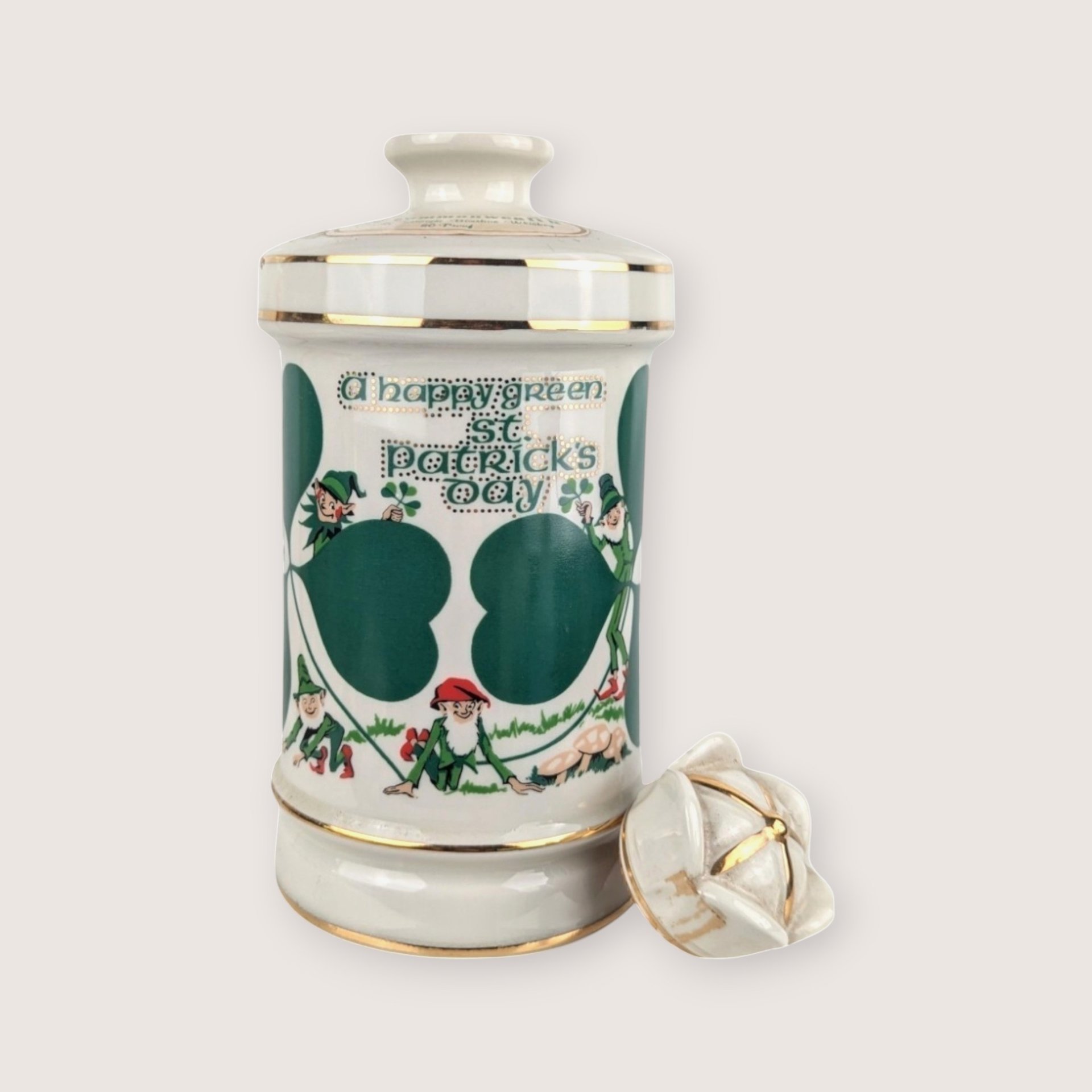 White ceramic Old Commonwealth Flowers of Ireland empty decanter with a green St Patricks Day graphic and broken stopper.
