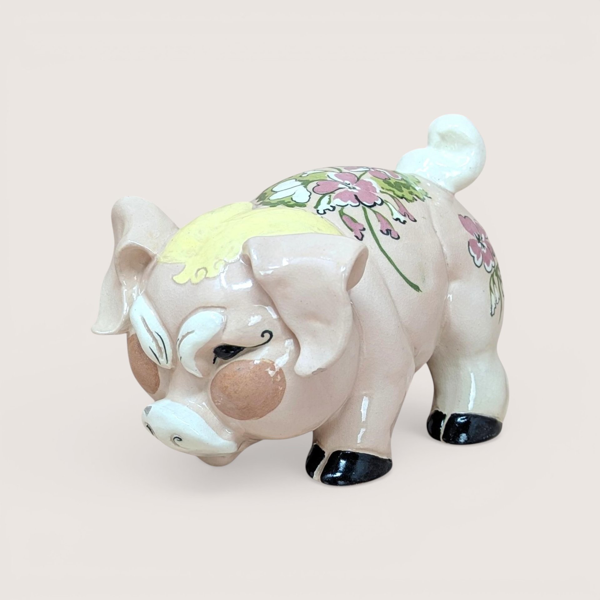 A vintage Kay Finch California pottery pig figurine with a pink floral pattern on its back and a humorous grumpy facial expression.