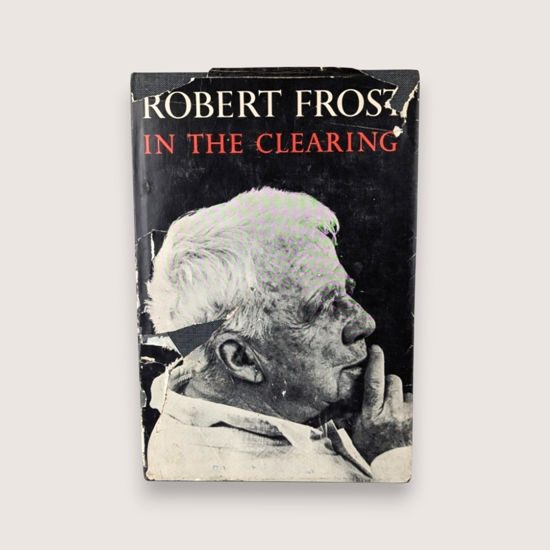 Distressed dust jacket of a 1962 Robert Frost poetry book titled In the Clearing featuring a black and white portrait.