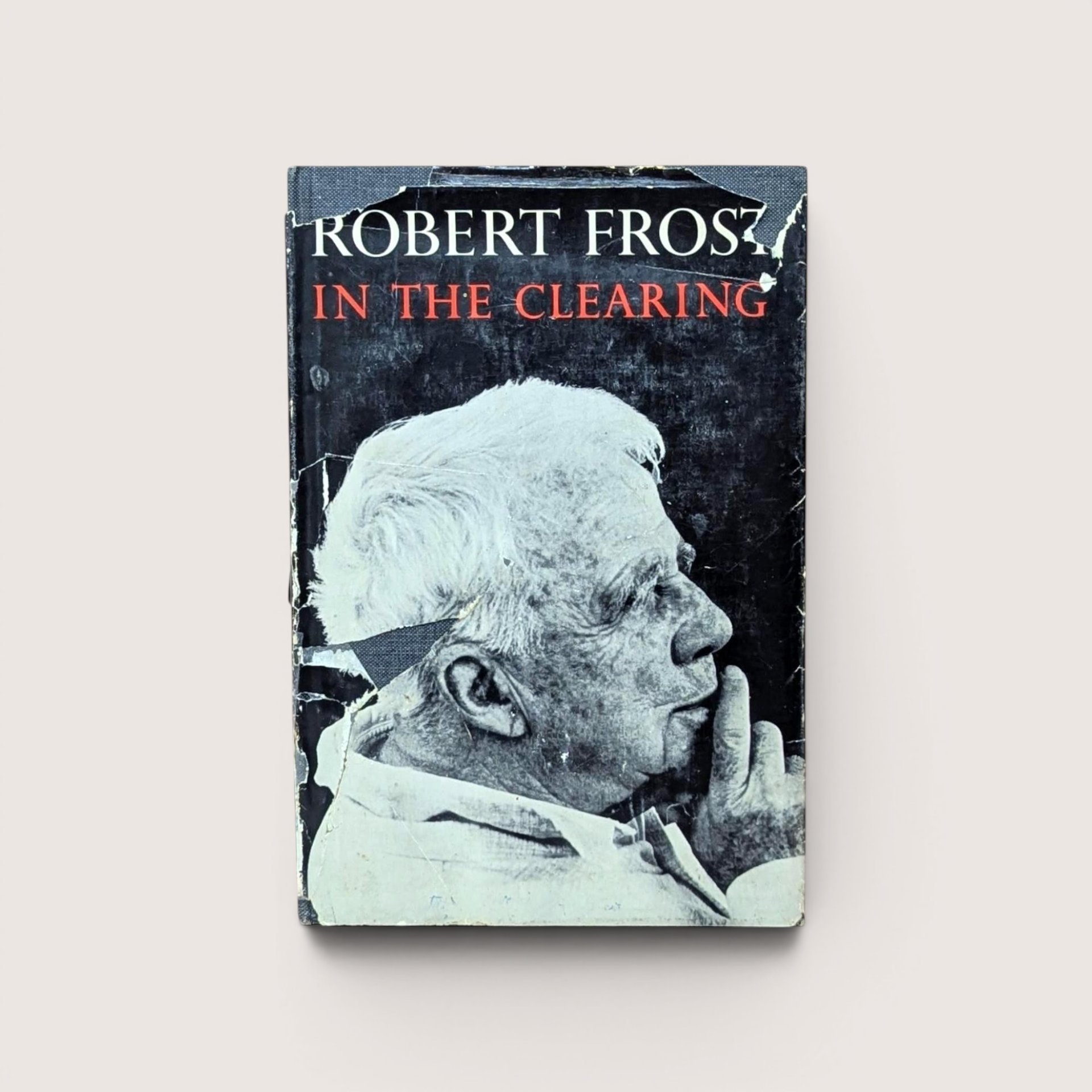 A vintage hardcover edition of In the Clearing by Robert Frost featuring a black and white portrait of the poet on a worn dust jacket