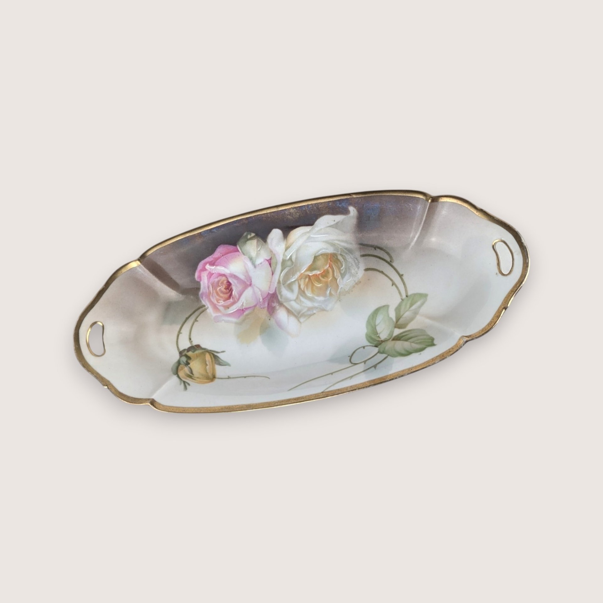 Antique porcelain celery dish from Suhl Germany featuring hand-painted roses and a gold-trimmed rim with handles.