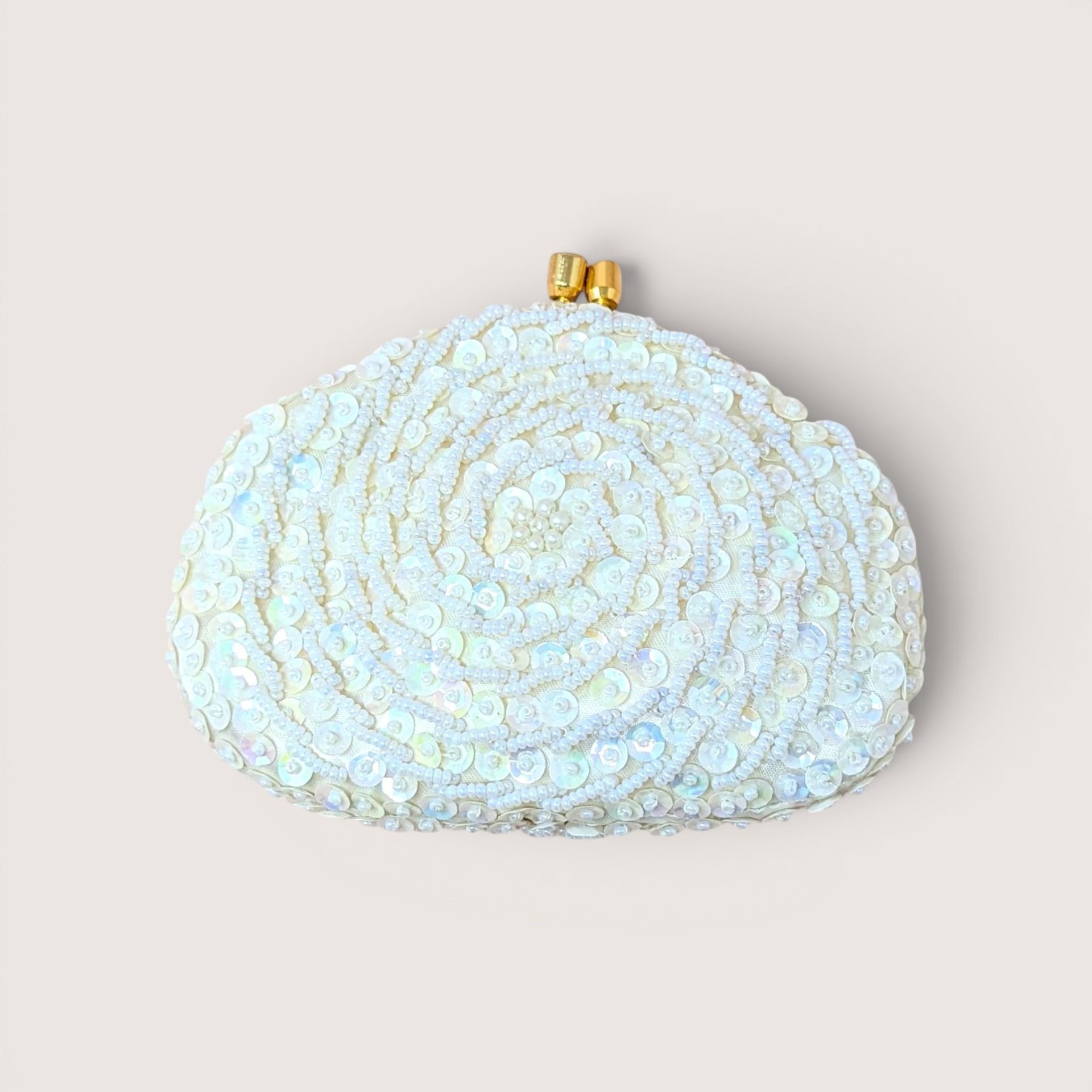 A white beaded and sequined clutch purse with a gold clasp, centered on a beige background.