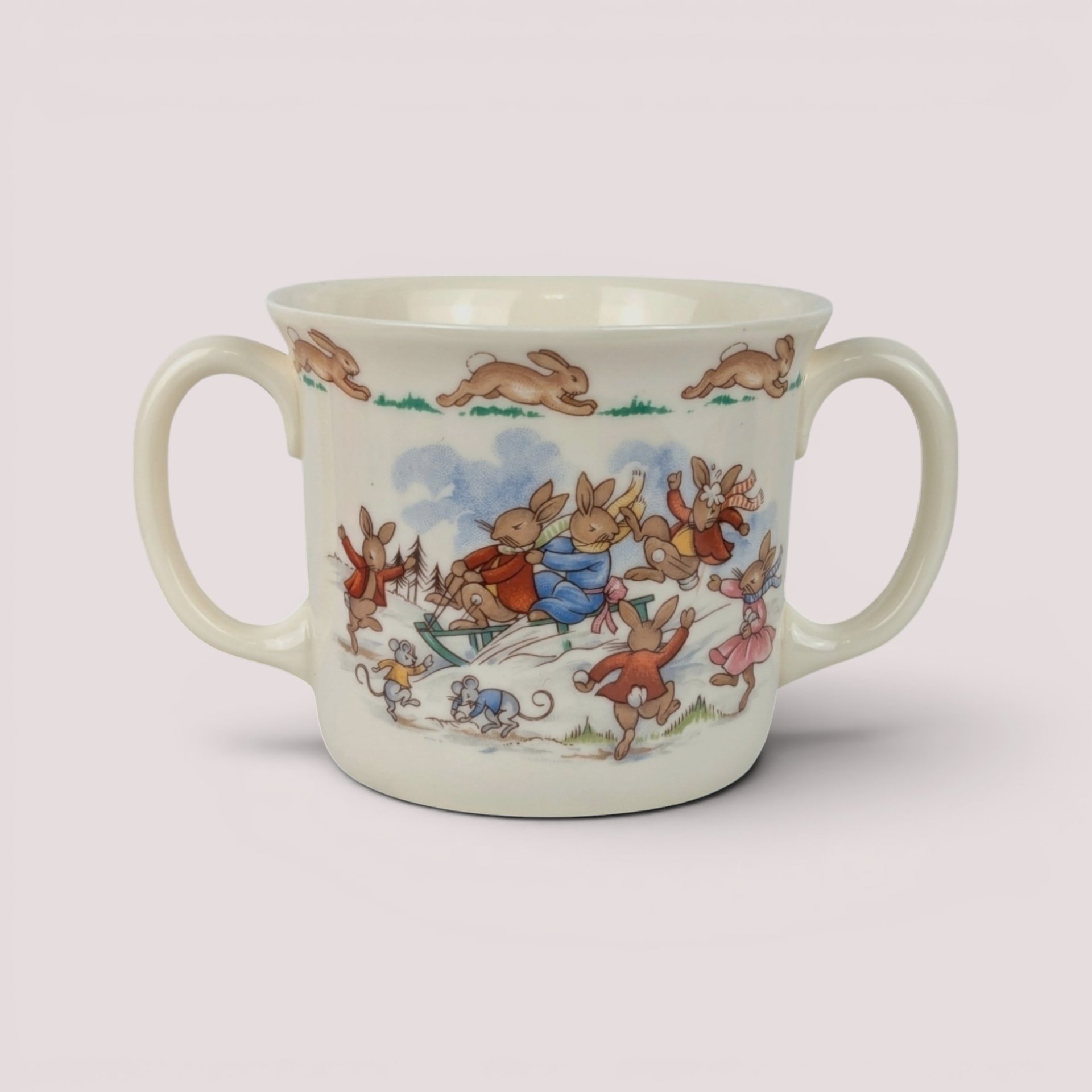 Vintage 1984 Royal Doulton Bunnykins two-handled ceramic cup featuring a colorful winter scene of rabbits sledding.