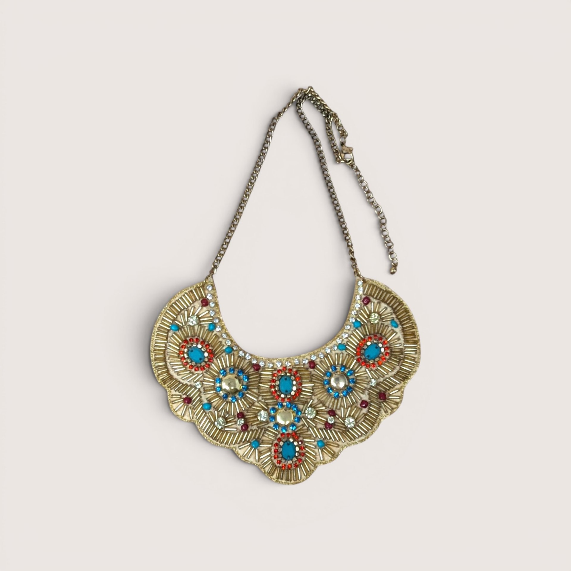 Intricate gold beaded bib necklace featuring turquoise, red, and blue accents with clear rhinestones.