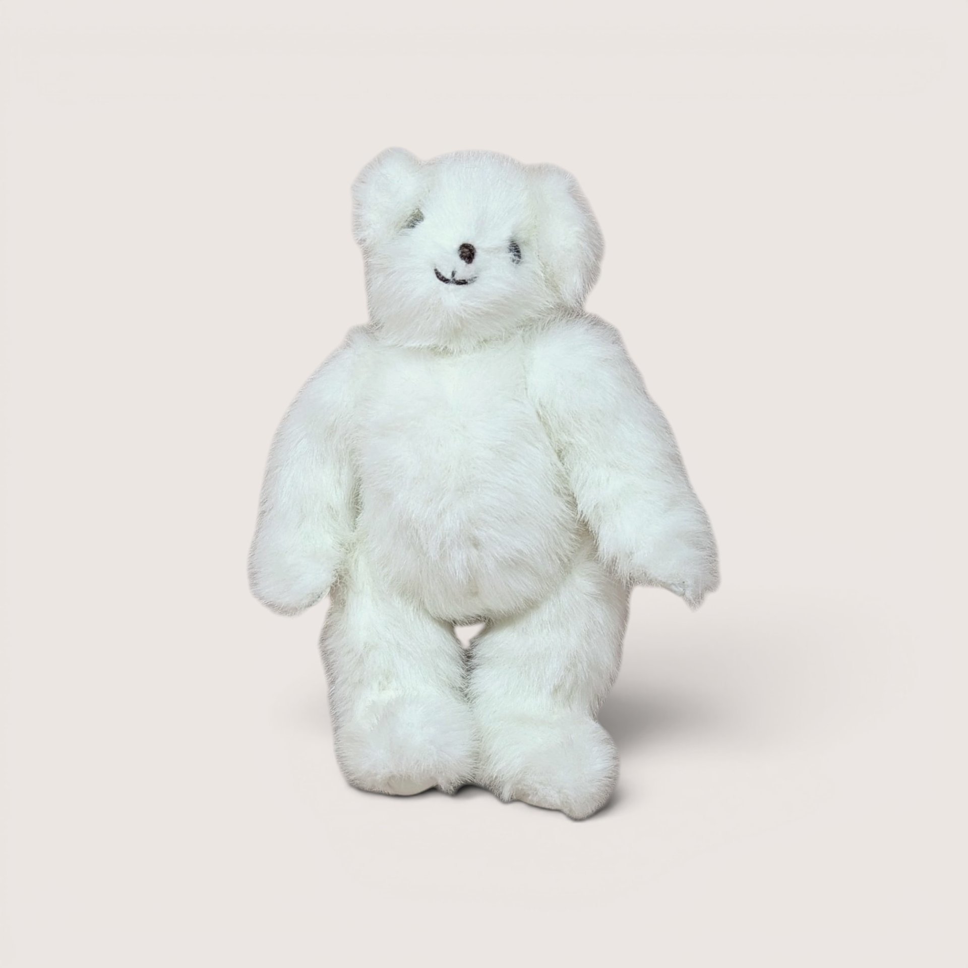 A fluffy white plush teddy bear standing upright and smiling, centered on a beige background.