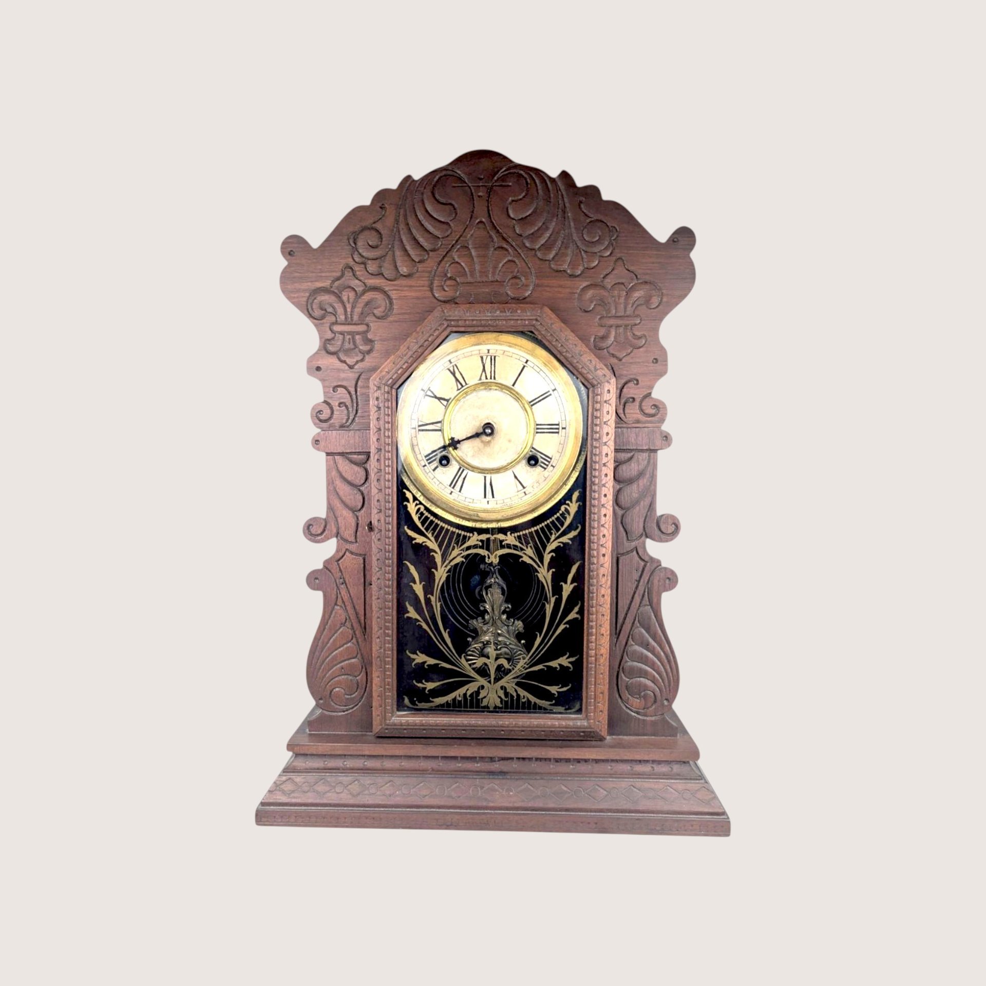 Antique Waterbury Tampa gingerbread parlor clock with an intricately carved walnut case and gold stenciled glass door.