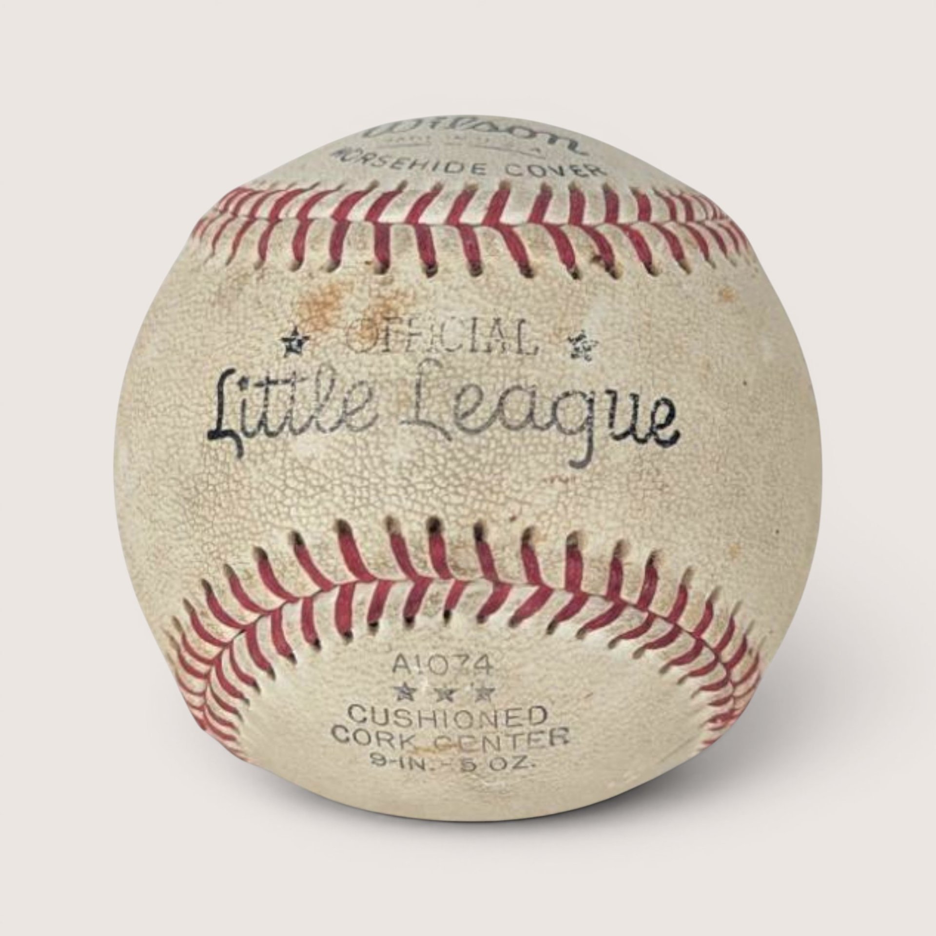 Vintage baseball with red stitching and a blue ink signature across the sweet spot, centered on a plain linen background.