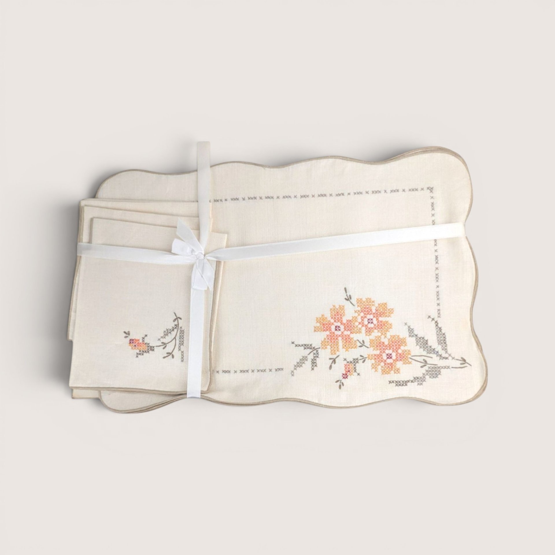 Vintage cream linen Bucilla placemats and napkins set featuring hand-embroidered cross-stitch orange flowers.