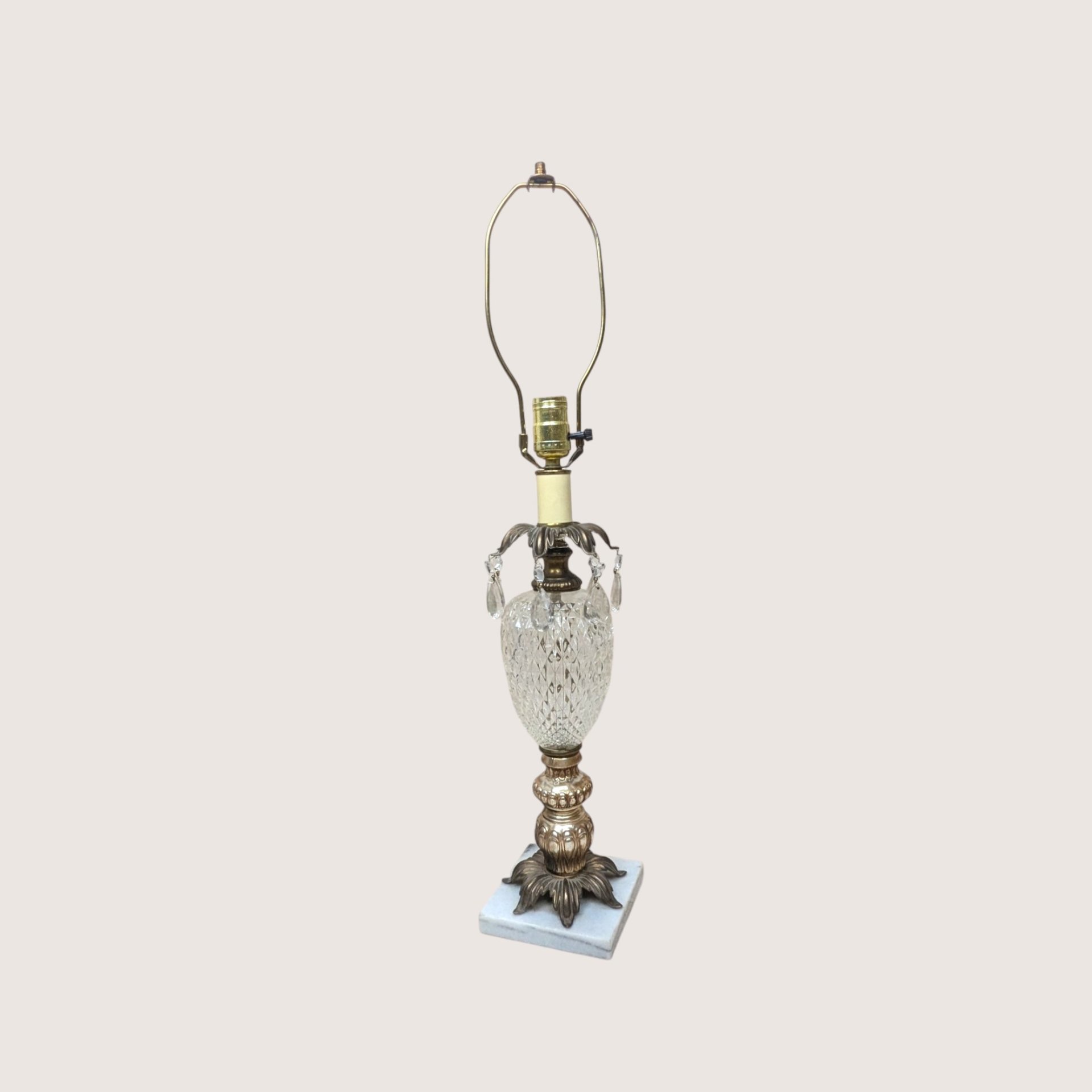 A vintage Hollywood Regency table lamp with a cut glass urn body and hanging crystal glass prisms.