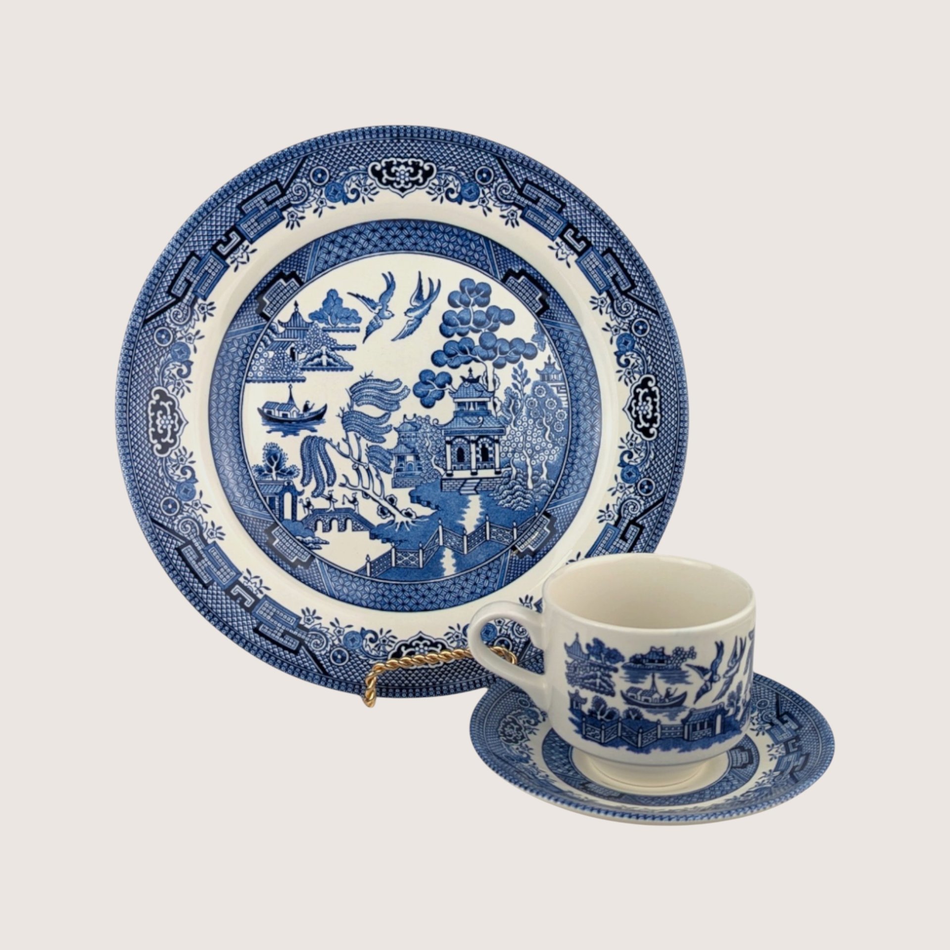 A vintage Churchill blue and white ceramic 3 piece Blue Willow set including a dinner plate, teacup, and saucer.