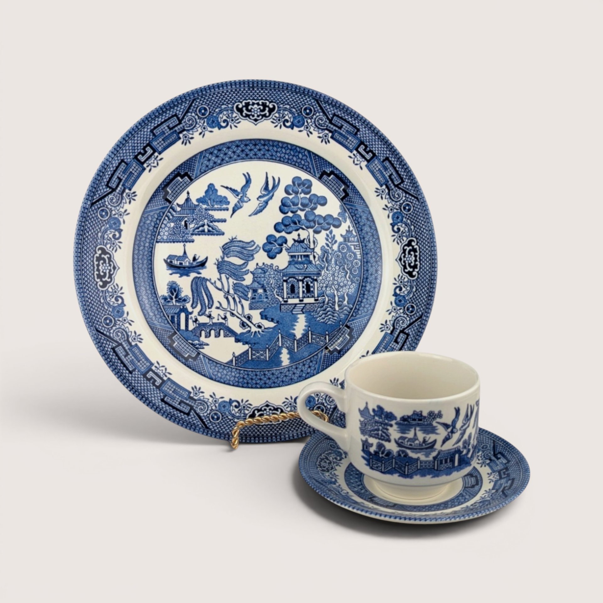 A vintage Churchill blue and white ceramic 3 piece Blue Willow set including a dinner plate, teacup, and saucer.