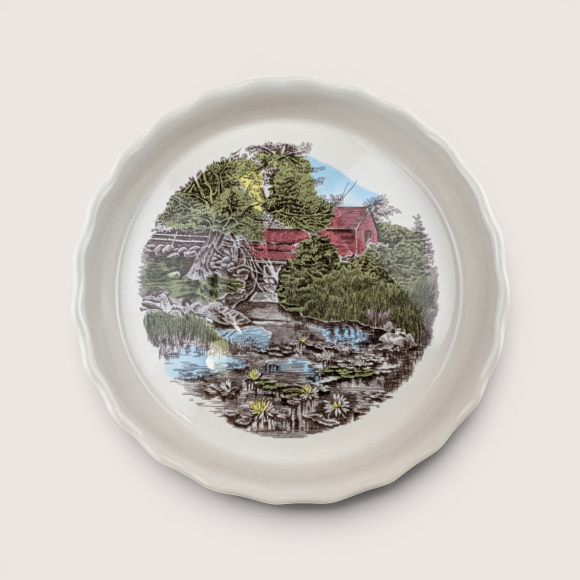 Vintage Johnson Brothers Friendly Village ceramic pie plate featuring a scenic red covered bridge illustration and scalloped edge.