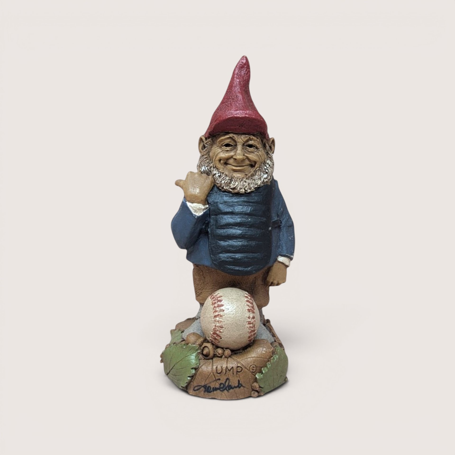 Vintage Tom Clark signed Ump baseball umpire gnome figurine standing behind a baseball on a linen background