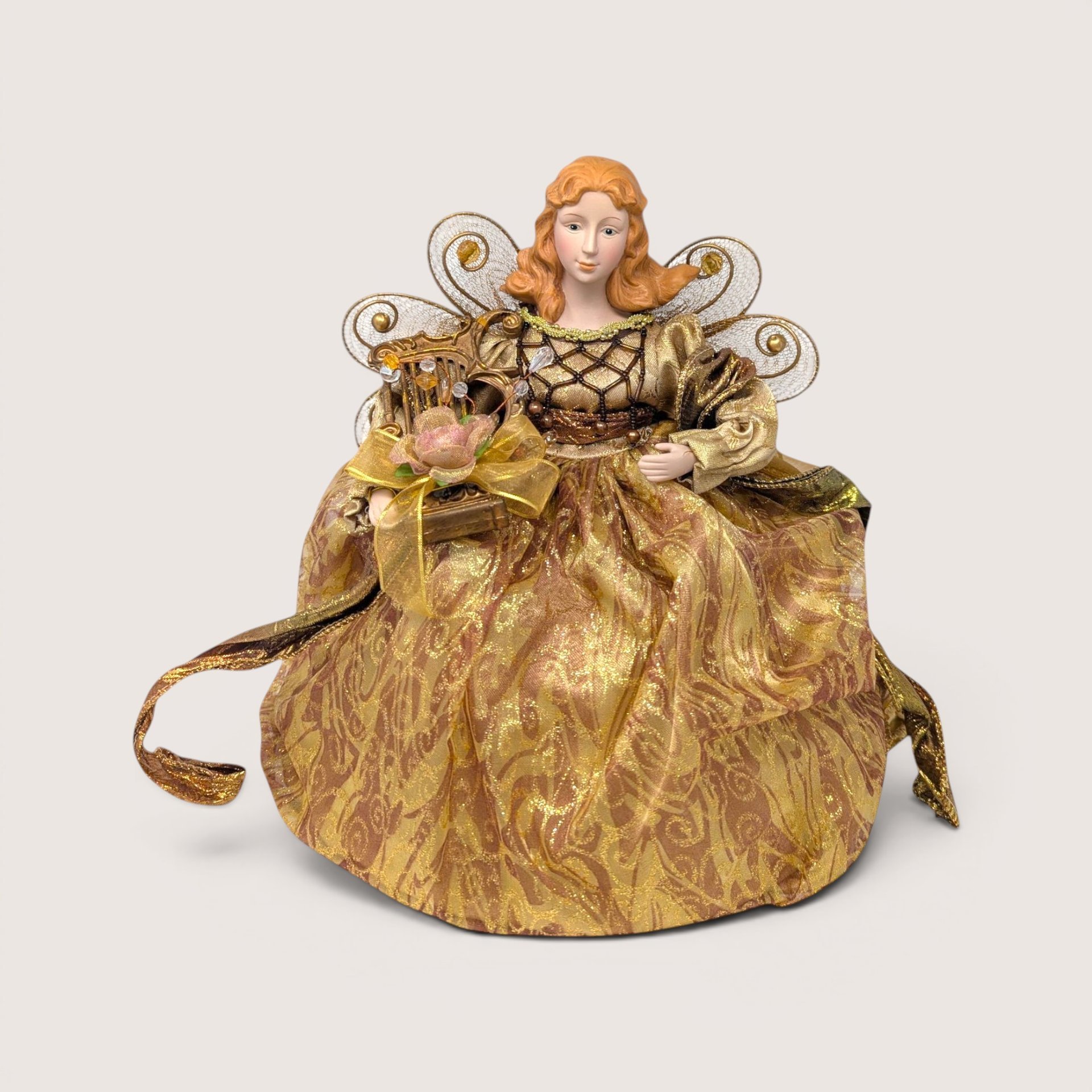 A vintage standing Christmas angel tree topper dressed in a gold metallic gown, holding a miniature harp.