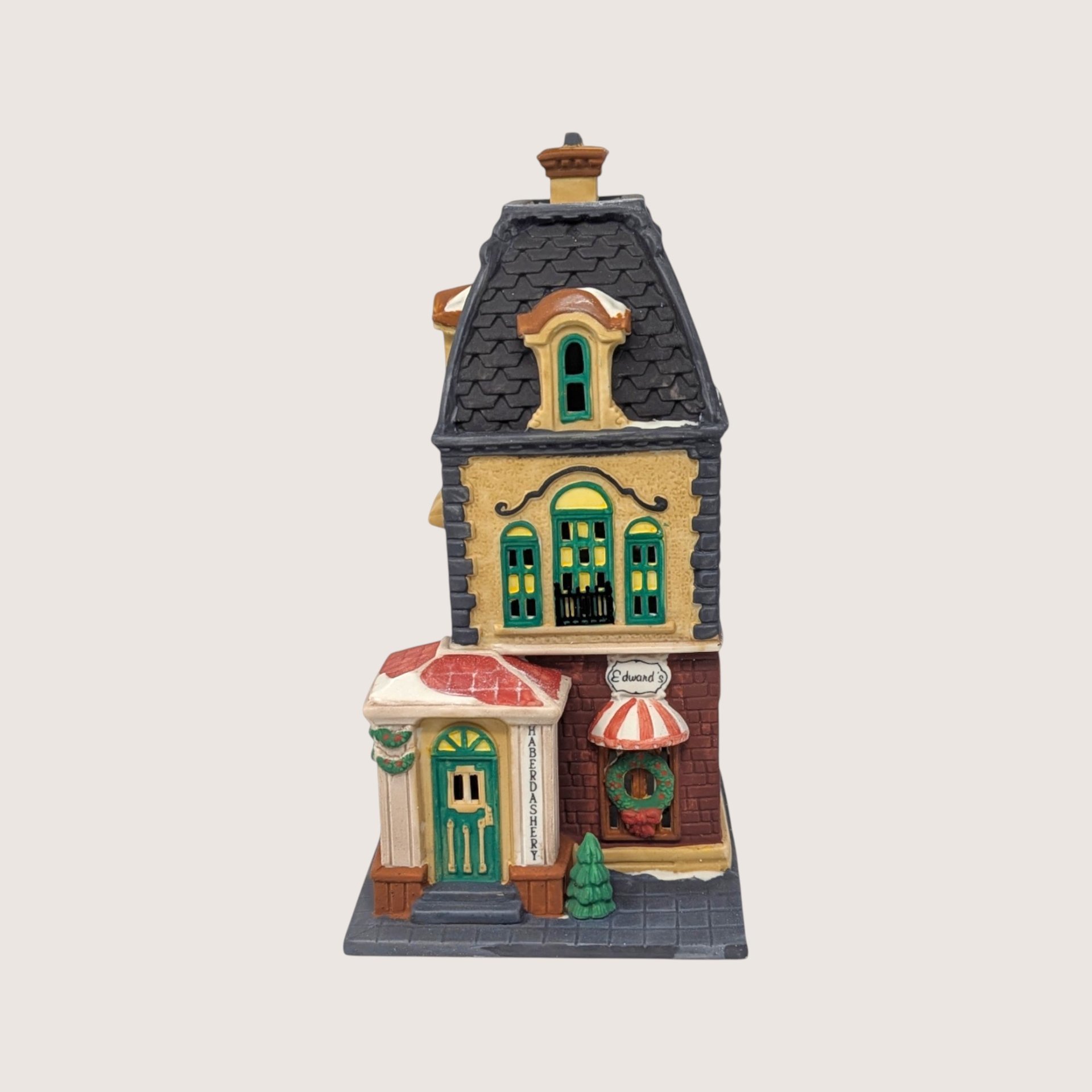 A handpainted porcelain Dept 56 Haberdashery metropolitan building on a linen background